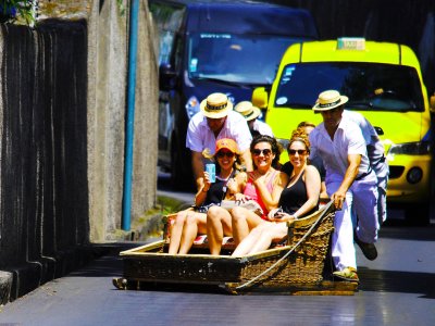 Ride in toboggan wooden sledge down asphalt road on Madeira